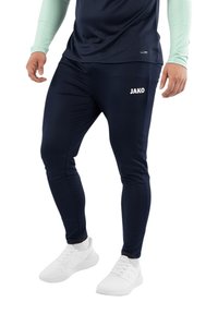 Marineblaue Sporthosen mit schmaler Passform, aus glattem Material. Mit dem weißen "JAKO"-Logo am oberen Oberschenkel. Tragen Sie dazu weiße Sneakers.