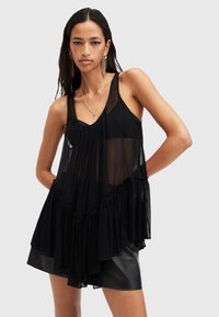 Black sleeveless top with a flowing design, made of sheer fabric. Features gathered accents and ruffled hem for added texture.