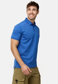 Polo à manches courtes en tissu tricoté bleu. Il présente un col, une patte de boutonnage à trois boutons et un logo orange sur la poche gauche.