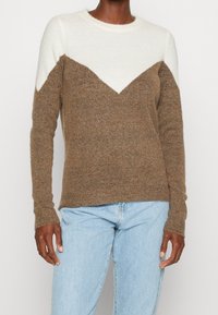 Brązowo-kremowy dziany sweter z motywem w jodełkę, z długimi rękawami i okrągłym dekoltem, wykonany z miękkiej, fakturowanej tkaniny.