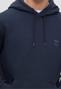 Navy blue hoodie in soft fabric with a front kangaroo pocket, adjustable drawstrings, and a small square logo on the chest.