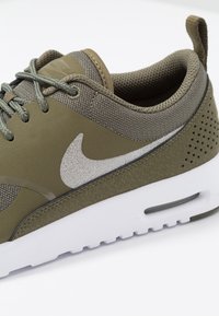 Nike sneakers med olivgrön mesh och syntetiskt ovandel, silverlogo, vit mellansole och texturerade detaljer. Har snörning och perforeringar.