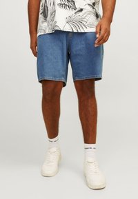 Džínové šortky světle modré barvy, volného střihu, s přímým střihem nohavic. Stylizované s vzorovanou košilí a bílými teniskami.