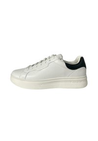 Sneaker bianca in pelle con finitura testurizzata, dotata di un accento nero sul tallone e di una suola bianca spessa. Lacci e logo del marchio visibili.