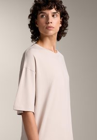 Svijetlobučasti oversized majica s okruglim izrezom i kratkim rukavima. Mekana, glatka tekstura; minimalistički dizajn bez uzoraka.