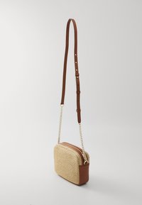 Tkaná crossbody taška v odstínech béžové a hnědé s hladkým hnědým koženým dnem, zlatým řetízkovým popruhem a se zipem nahoře. Texturovaný povrch.