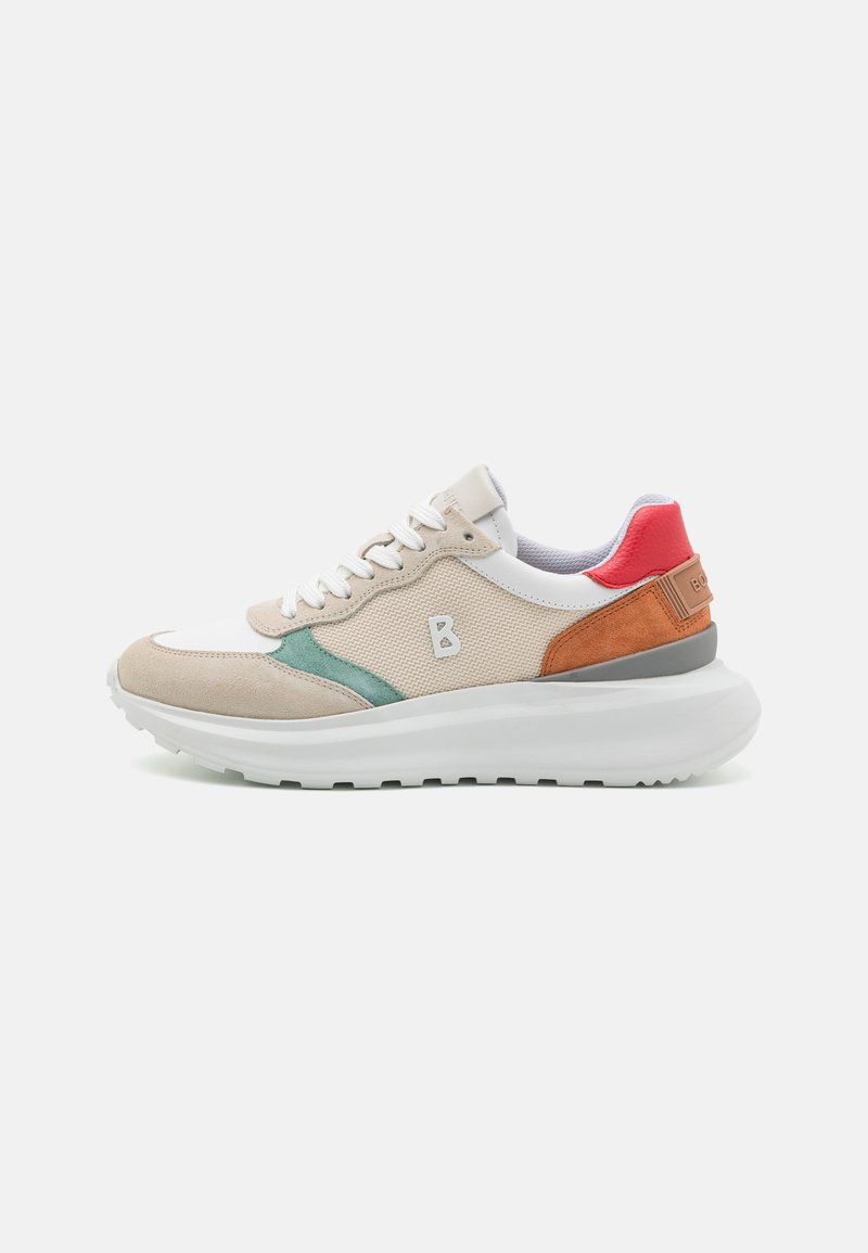 Baskets de sport beiges avec une tige texturée, des accents verts et orange, et une épaisse semelle blanche avec un motif de semelle.