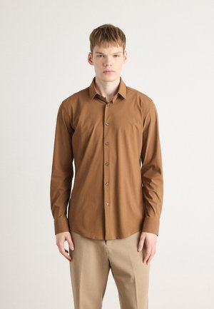 Camisa de manga larga marrón en tejido ligero con un cuello abotonado y tapeta delantera; presenta botones marrones y un corte entallado.