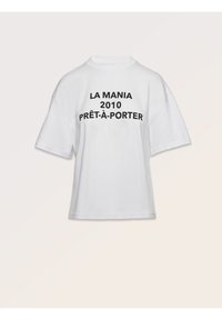 Bílý bavlněný tričko s oversized krátkými rukávy, na přední straně výrazně potištěným černým textem: "LA MANIA 2010 PRÊT-À-PORTER".