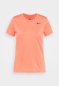 Camiseta Nike en vibrante color coral, de mangas cortas, con cuello redondo, fabricada en una tela suave, que presenta un acento de logo negro en el lado izquierdo del pecho.