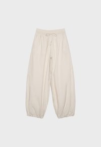 Pantalon beige à jambes larges avec taille élastique et cordon de serrage, doté de poignets élastiques froncés aux chevilles pour une coupe décontractée.