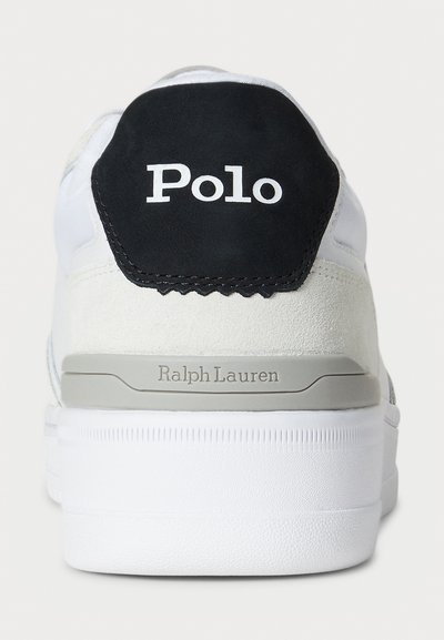 White sneaker with a black suede heel tag featuring "Polo" logo, and gray accents. Textured material with rubber sole and stitching details.