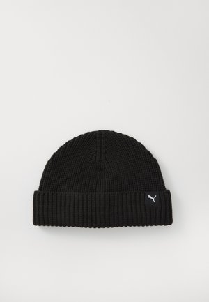 Black knitted beanie made of ribbed material, featuring a folded hem and a small white logo tag on the side.