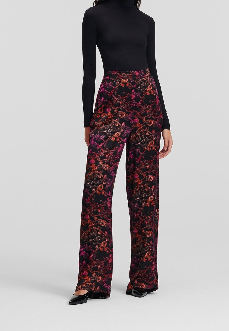Un haut noir à manches longues associé à un pantalon large illustré d'un imprimé floral et géométrique aux teintes rouges, roses et oranges.