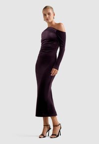 Pielāgota violeta zīda kleita ar plecus atklājošu dizainu un garām piedurknēm; ar savilkuma detaļu viduklī un taisnu apakšmalu.