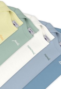 Τέσσερα μπλουζάκια σε παστέλ αποχρώσεις: κίτρινο, πράσινο, λευκό και μπλε. Κάθε ένα έχει κεντημένο κείμενο στο μπροστινό μέρος σε αντίστοιχα χρώματα.