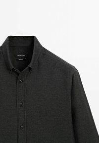 Chemise à boutons gris foncé avec col, étiquette de marque "Massimo Dutti" et manches longues, présentée sur un fond blanc.