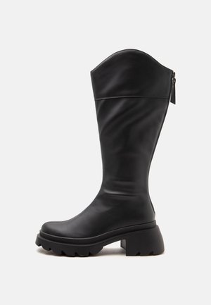 Botte en cuir noire mi-mollet avec semelle épaisse, talon carré et fermeture éclair à l’arrière.