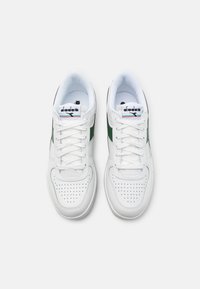 White leather sneakers with a green side stripe, perforated toe, and white laces. Features a cushioned interior and branded tongue label.