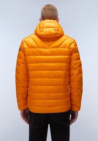 Giacca a vento arancione con cuciture orizzontali, cappuccio e texture liscia. Presenta una toppa sulla spalla sinistra e un taglio di lunghezza media.