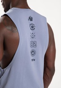 Lichtpaarse mouwloze tanktop met grafische prints. Bevat logo-ontwerpen, het nummer 82 en zwarte accenten op de achterkant. Zachte stofstructuur.