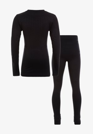 Ensemble haut à manches longues noir et leggings fabriqué dans un tissu texturé et extensible, avec une coupe ajustée et des accents décoratifs sur les épaules et les jambes.