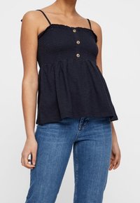 Marineblaues, ärmelloses Oberteil mit einem gerafften Oberteil, gerüschtem Ausschnitt und drei Knöpfen auf der Vorderseite. Ausgestellt geschnitten, aus leichtem Stoff gefertigt.