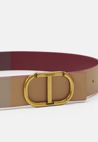 Cintura in pelle bicolore con fibbia ovale in tonalità oro con "TWINSET" inciso. Colori: marrone chiaro e bordeaux, con texture liscia.