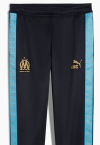Pantalones deportivos negros con logotipos dorados, presentando una franja lateral con un patrón azul y una cintura elástica para mayor comodidad.