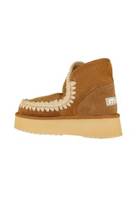 Botas de tobillo de ante marrón con un ribete trenzado decorativo y una suela de goma texturizada de color claro. Presenta un parche con el logotipo en el talón.