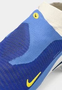Sapatilha de desporto azul com parte superior em malha texturizada em tons mais escuros e mais claros, logotipo da Nike amarelo e gola branca.