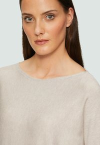 Maglione color beige chiaro con ampio scollo a barca e un sottile motivo a costine. Maniche aderenti e una vestibilità rilassata aumentano comfort e stile.