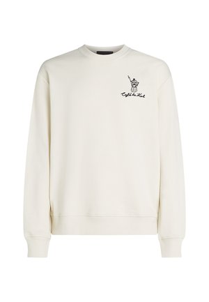 Sweatshirt crème en tissu doux, avec un col rond côtelé et des poignets. Présente un design graphique noir sur la poitrine gauche.