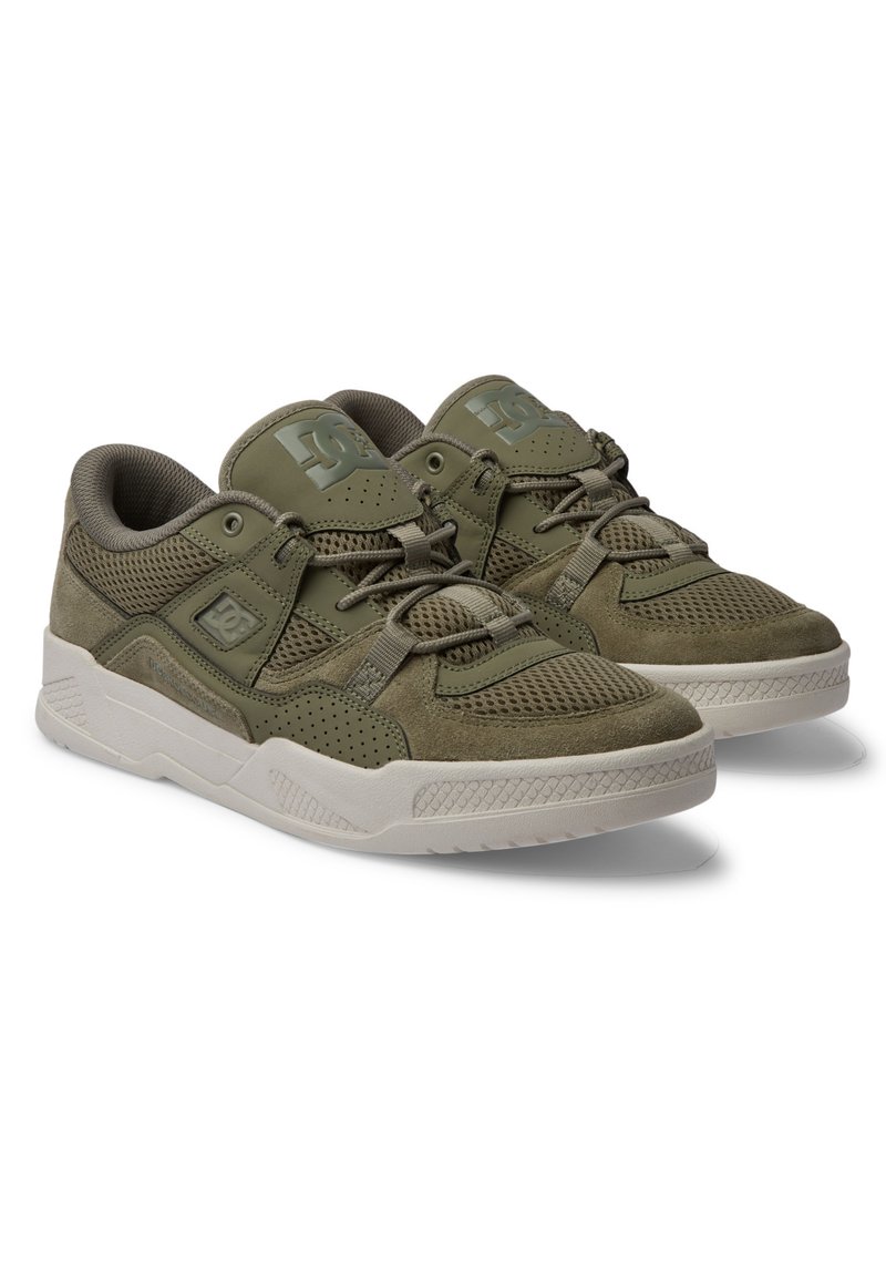 Zapatillas de color verde oliva con parte superior de ante y malla, cuello acolchado y detalles perforados. Suela de goma blanca con agarre texturizado.