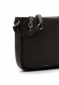 Borsetta da polso in pelle nera texturizzata con charm a catena argentata e piccolo logo "Suri Frey" sul bordo inferiore anteriore.