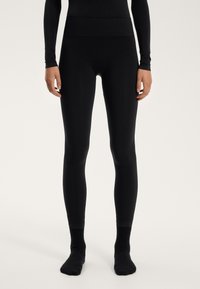 Zwarte leggings van glad, rekbaar materiaal met een hoge tailleband. Geen zichtbare naden of patronen; aansluitende pasvorm tot aan de enkels.