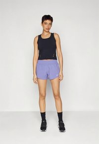 Must musta sportlik lühike top lõigete ja heleroosade lühikeste pükstega, millel on elastne vöökoht ja väike valge logo. Mustad sokid ja tossud.