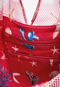 Rote Stofftasche mit blauen maritimen Mustern, ausgestattet mit Netzträgern, einer Reißverschlusstasche und einer strukturierten Innenseite.