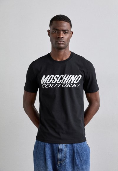 T-shirt in cotone nero con bold scritta bianca "MOSCHINO COUTURE!" sulla parte frontale. Design aderente con maniche corte e scollo rotondo.