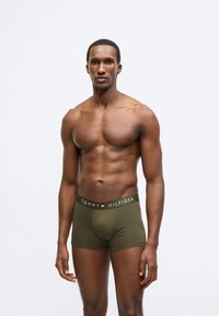 Λαδί πράσινα ανδρικά μποξεράκια με φαρδιά μαύρη μέση που φέρει το όνομα της μάρκας "TOMMY HILFIGER" σε λευκό. Μαλακό, ελαστικό ύφασμα.