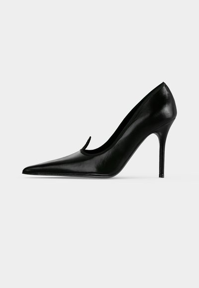 Chaussure à talon haut en cuir noir avec bout pointu et talon aiguille fin, montrée de profil sur un fond clair uni.