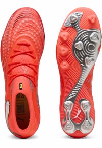 Jalkapallokengät kirkkaan oransseina, joissa on teksturoitu päällinen, tyylikäs muotoilu, heijastavat yksityiskohdat ja nastallinen kumipohja.