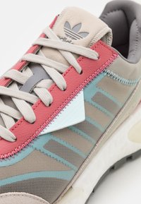 Sneakern har en ovandel i mesh och läder med rosa, grå och akvafärgade detaljer. Märkbar vit triangulär detalj och texturerad sula.