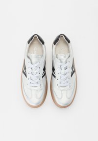 Baskets de sport argentées avec accents noirs, à lacets à l'avant, tige en cuir lisse et semelle en gomme. Design classique avec des détails rayés.