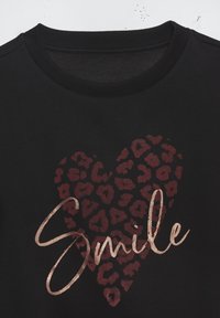 Črna kapuca z leopardjim vzorcem srčne oblike v burgundski barvi in besedo "Smile" v metalno rozo zlatih črkah. Mehka tekstura.