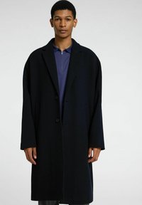 Long pardessus bleu marine en mélange de laine, avec un col cranté, deux poches avant et une fermeture à boutons, doté d'une coupe décontractée.