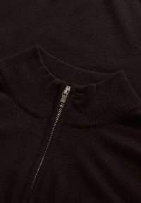 Schwarzer Strickpullover mit hohem Kragen und einem Reißverschluss auf der Vorderseite. Weicher Stoff mit gerippten Akzenten am Kragen und Saum.