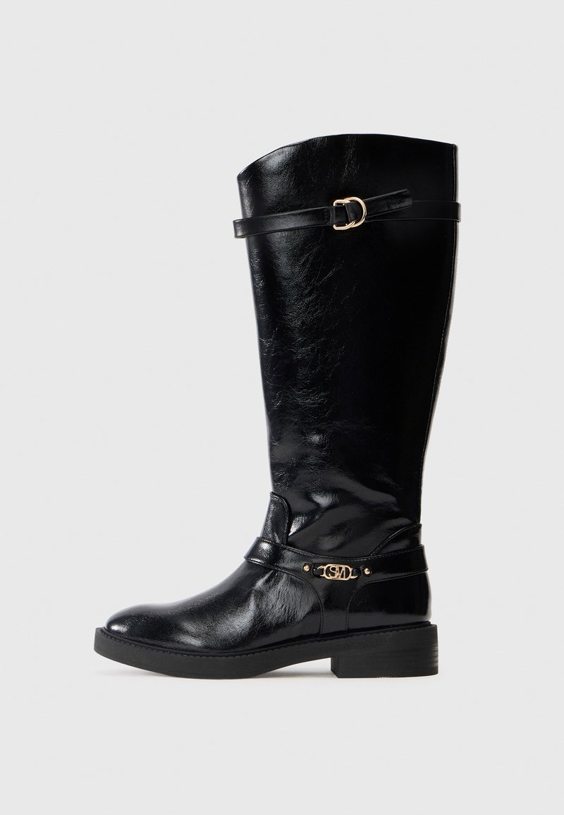 Botte noire en cuir montant jusqu'au genou avec un petit talon, boucle décorative en or près de la cheville, et une sangle avec détail de boucle en or en haut.