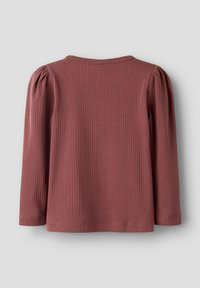 Dug dugi majica u prašnjavo ružičastoj boji s rebrastom teksturom, koja ima lagano pufnaste ramena i okrugli izrez. Mekani materijal i ležeran kroj.