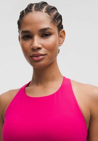 Top ajustado sin mangas de color rosa con un cuello alto, textura suave y sisas redondeadas; situado contra un fondo neutro.